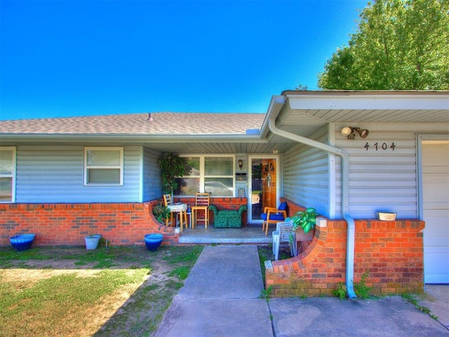 4704 Lisa Ln, Oklahoma City, OK 73115 - property entrance with covered porch, brick siding, and roof with shingles
