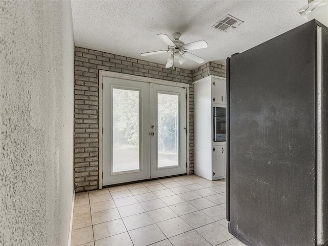 4704 Lisa Ln, Oklahoma City, OK 73115 - doorway with french doors, a ceiling fan, light tile patterned flooring, a textured ceiling, and brick wall