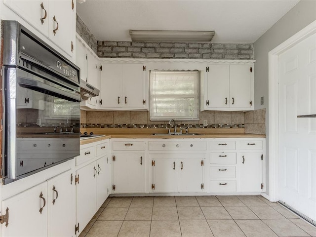 4704 Lisa Ln, Oklahoma City, OK 73115 - kitchen featuring oven, tasteful backsplash, white cabinets, and under cabinet range hood