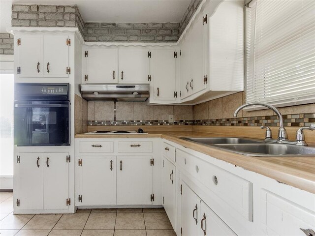 4704 Lisa Ln, Oklahoma City, OK 73115 - kitchen with oven, under cabinet range hood, light tile patterned flooring, and white cabinetry
