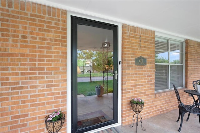 doorway to property with brick siding and covered porch