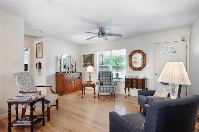 sitting room with a ceiling fan, light wood-type flooring, and baseboards