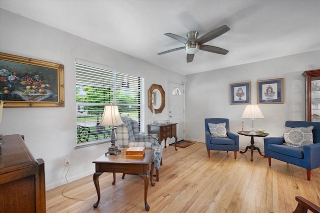 living area with a ceiling fan, light wood finished floors, and baseboards