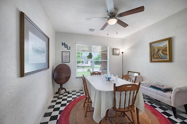 dining area with tile patterned floors, ceiling fan, and a textured wall