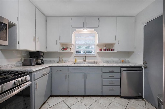 kitchen with stainless steel appliances, a sink, gray cabinets, and open shelves