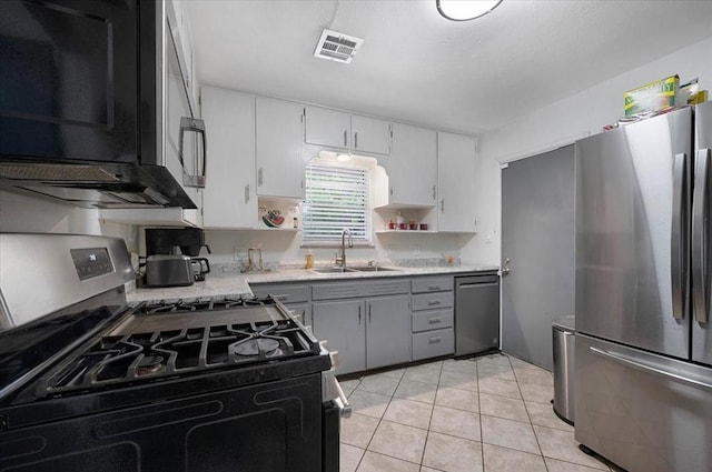 kitchen with appliances with stainless steel finishes, a sink, light tile patterned floors, open shelves, and white cabinetry