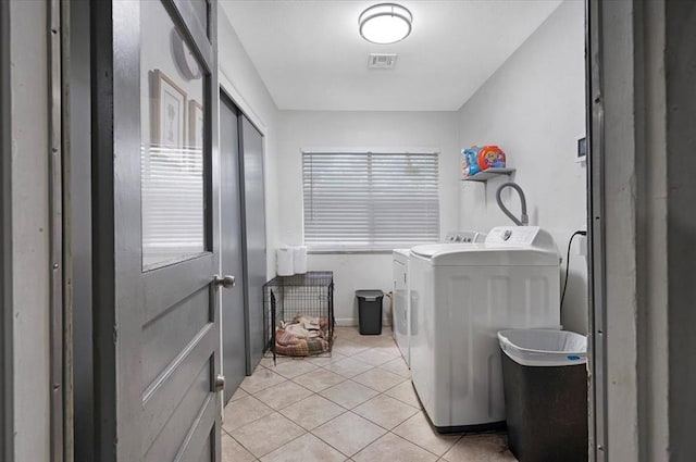 clothes washing area featuring washer and clothes dryer and light tile patterned flooring