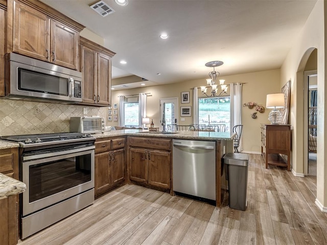 15101 SE 58th St, Choctaw, OK 73020 - kitchen featuring stainless steel appliances, light wood finished floors, a peninsula, a sink, and decorative backsplash