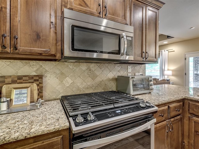 15101 SE 58th St, Choctaw, OK 73020 - kitchen with stainless steel appliances, decorative backsplash, and light stone countertops