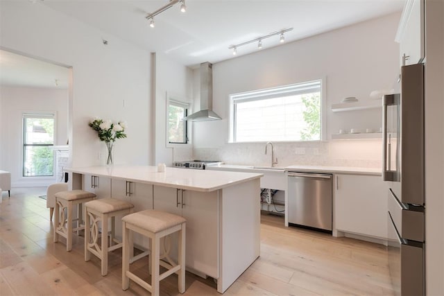 614 NW 8th St Unit 1-4, Oklahoma City, OK 73102 - kitchen featuring appliances with stainless steel finishes, wall chimney exhaust hood, white cabinetry, light countertops, and decorative backsplash