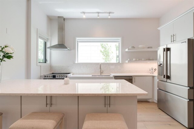 614 NW 8th St Unit 1-4, Oklahoma City, OK 73102 - kitchen featuring stainless steel appliances, wall chimney range hood, a sink, and decorative backsplash