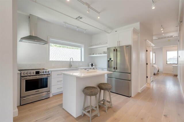 614 NW 8th St Unit 1-4, Oklahoma City, OK 73102 - kitchen with stainless steel appliances, track lighting, wall chimney range hood, a sink, and white cabinets