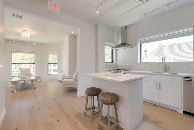614 NW 8th St Unit 1-4, Oklahoma City, OK 73102 - kitchen featuring rail lighting, wall chimney exhaust hood, a sink, dishwasher, and a kitchen breakfast bar