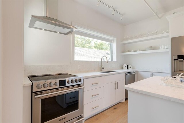 614 NW 8th St Unit 1-4, Oklahoma City, OK 73102 - kitchen with stainless steel appliances, wall chimney range hood, open shelves, white cabinetry, and a sink