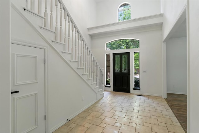 entryway with a high ceiling, stone tile flooring, baseboards, and stairs