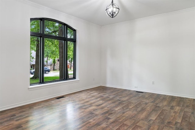 empty room with healthy amount of natural light, dark wood-style flooring, a chandelier, and ornamental molding