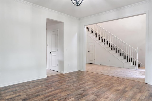 unfurnished living room with wood finished floors, stairs, ornamental molding, and baseboards