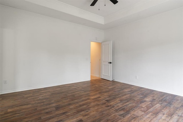 empty room featuring wood finished floors, ceiling fan, baseboards, a tray ceiling, and ornamental molding