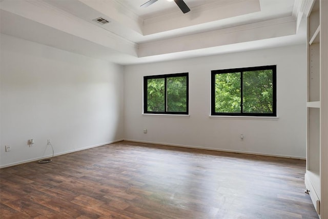 spare room with a raised ceiling, crown molding, wood finished floors, a ceiling fan, and baseboards