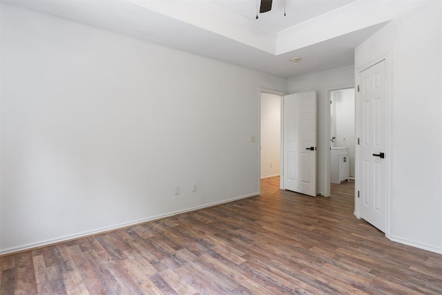 unfurnished bedroom featuring wood finished floors, baseboards, ceiling fan, a tray ceiling, and crown molding