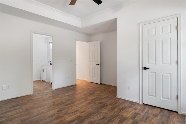 unfurnished bedroom with ornamental molding, dark wood-style floors, connected bathroom, baseboards, and a ceiling fan