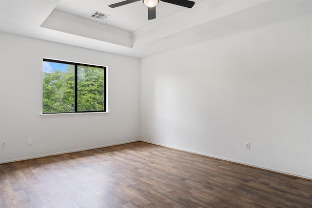 spare room featuring a raised ceiling, wood finished floors, ceiling fan, crown molding, and baseboards