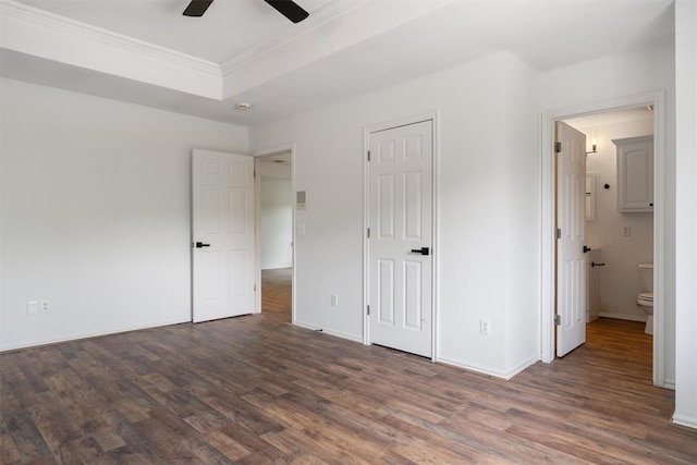 unfurnished bedroom featuring wood finished floors, ornamental molding, baseboards, ensuite bath, and ceiling fan