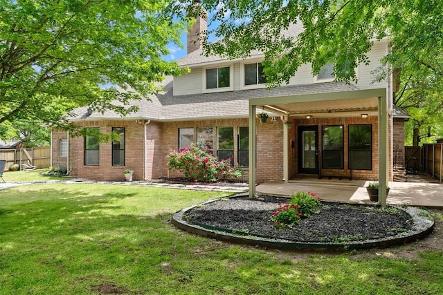 rear view of house with a patio area, brick siding, a chimney, and roof with shingles