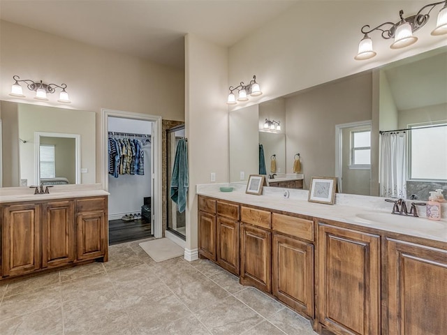 bathroom with a shower stall, double vanity, and a spacious closet