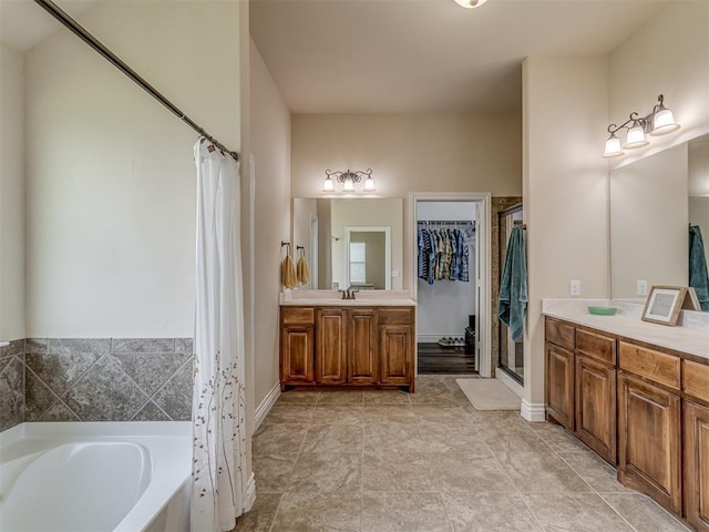 bathroom featuring a garden tub, a shower stall, vanity, a walk in closet, and baseboards