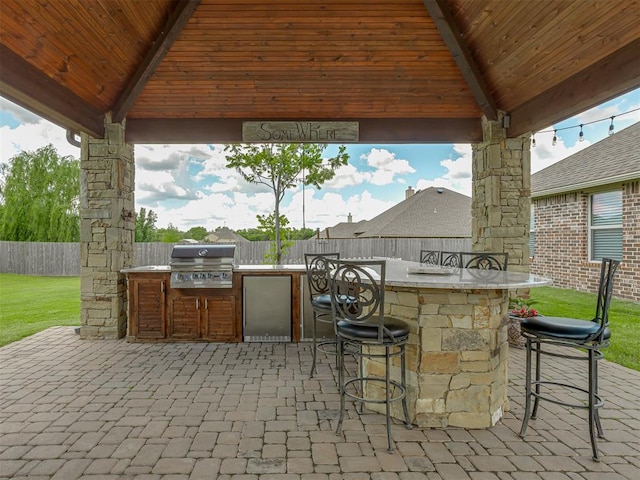 view of patio / terrace featuring a gazebo, an outdoor kitchen, grilling area, and a fenced backyard