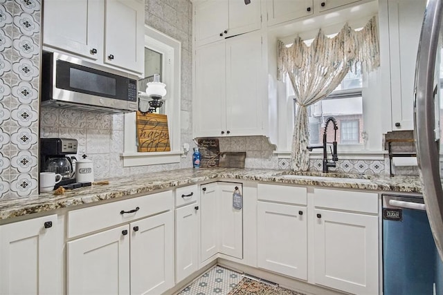 3715 N Mckinley Ave, Oklahoma City, OK 73118 - kitchen with appliances with stainless steel finishes, a sink, white cabinetry, and tasteful backsplash