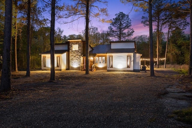 view of front of property with stone siding, metal roof, and driveway
