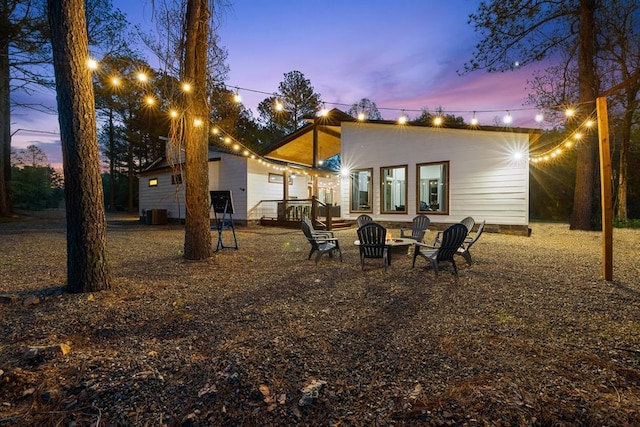 back of property with an outdoor fire pit and cooling unit