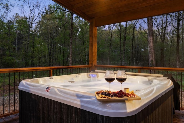 deck featuring a hot tub and a forest view