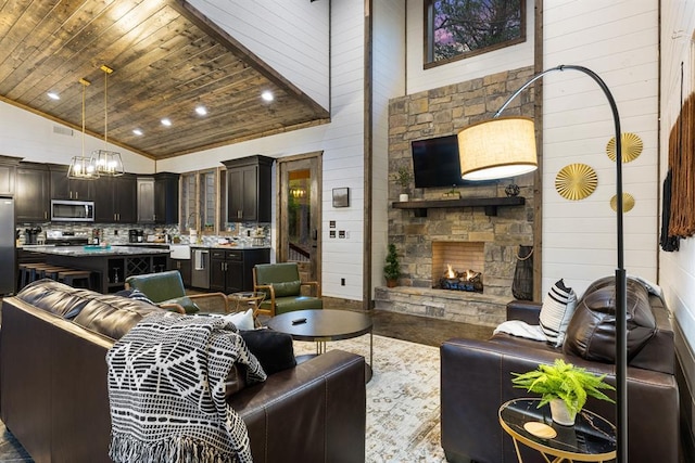 living area with wood walls, a fireplace, wooden ceiling, high vaulted ceiling, and a chandelier