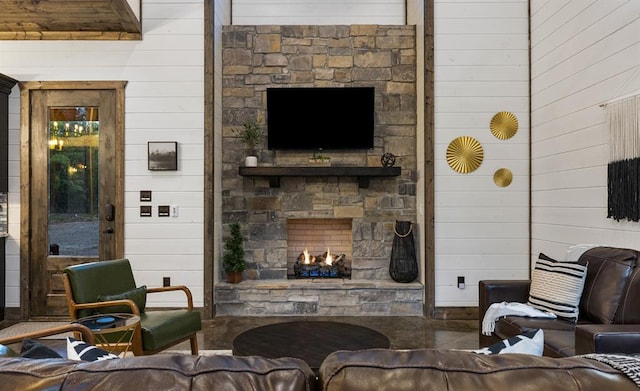 living room with wooden walls and a stone fireplace