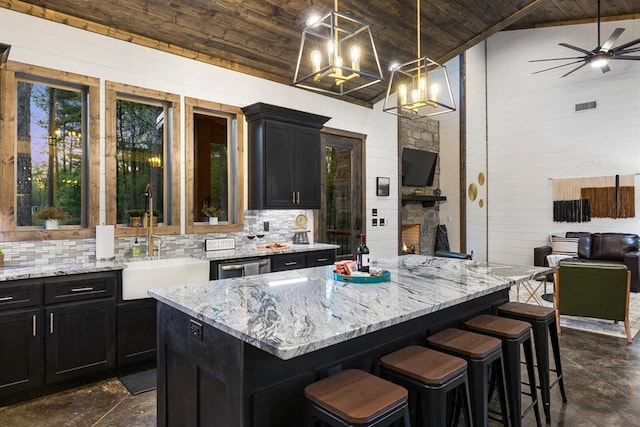 kitchen featuring wood ceiling, dark cabinets, backsplash, vaulted ceiling, and light stone countertops