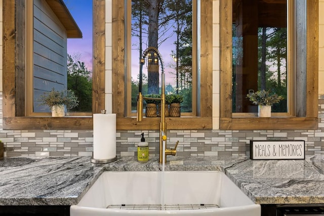 kitchen view of tasteful backsplash, a sink, and stone countertops