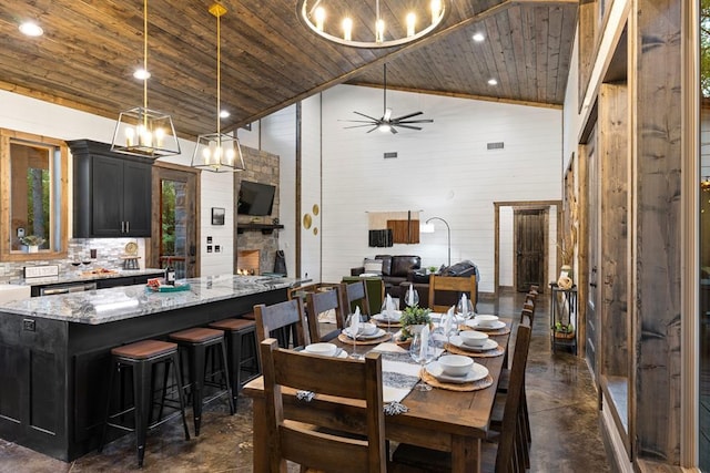 dining room featuring finished concrete flooring, wooden ceiling, a chandelier, high vaulted ceiling, and ceiling fan