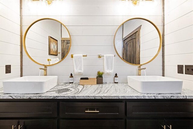 full bathroom featuring double vanity and wooden walls
