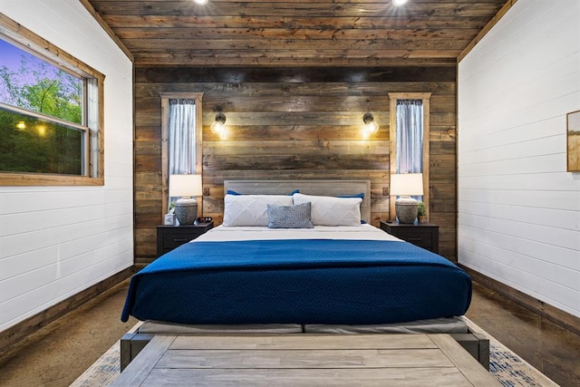 bedroom with wooden walls, wooden ceiling, baseboards, and concrete flooring