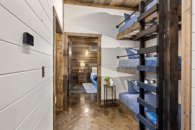 corridor with wooden walls and finished concrete flooring