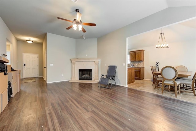 12032 SW 10th St, Yukon, OK 73099 - living room with a ceiling fan, wood finished floors, a fireplace with flush hearth, lofted ceiling, and a chandelier
