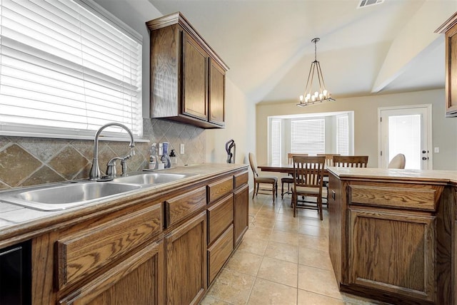12032 SW 10th St, Yukon, OK 73099 - kitchen featuring tasteful backsplash, hanging light fixtures, light tile patterned floors, brown cabinets, and vaulted ceiling