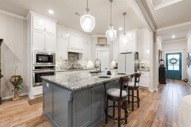 8208 Poplar Dr, Edmond, OK 73034 - kitchen with appliances with stainless steel finishes, light wood finished floors, white cabinets, backsplash, and recessed lighting