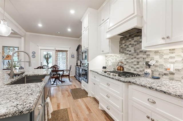 8208 Poplar Dr, Edmond, OK 73034 - kitchen featuring appliances with stainless steel finishes, a sink, white cabinetry, decorative backsplash, and custom exhaust hood