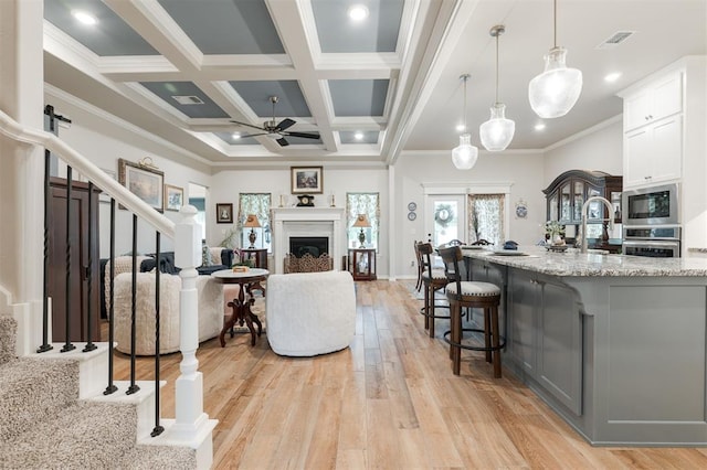 8208 Poplar Dr, Edmond, OK 73034 - living area with a ceiling fan, light wood finished floors, stairs, crown molding, and a fireplace