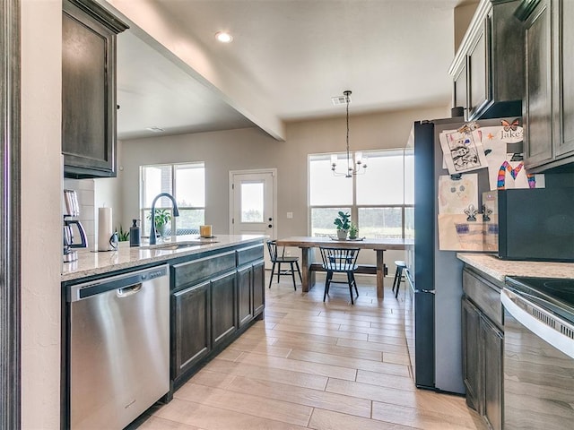 6965 Seabiscuit Ln, Guthrie, OK 73044 - kitchen featuring stainless steel dishwasher, a sink, beam ceiling, light stone counters, and light wood-style floors
