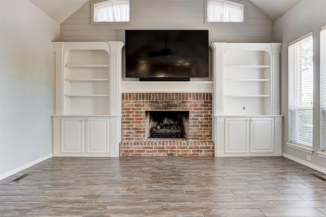 3401 Fox Hill Ter, Edmond, OK 73034 - unfurnished living room featuring lofted ceiling, wood finished floors, a brick fireplace, and healthy amount of natural light